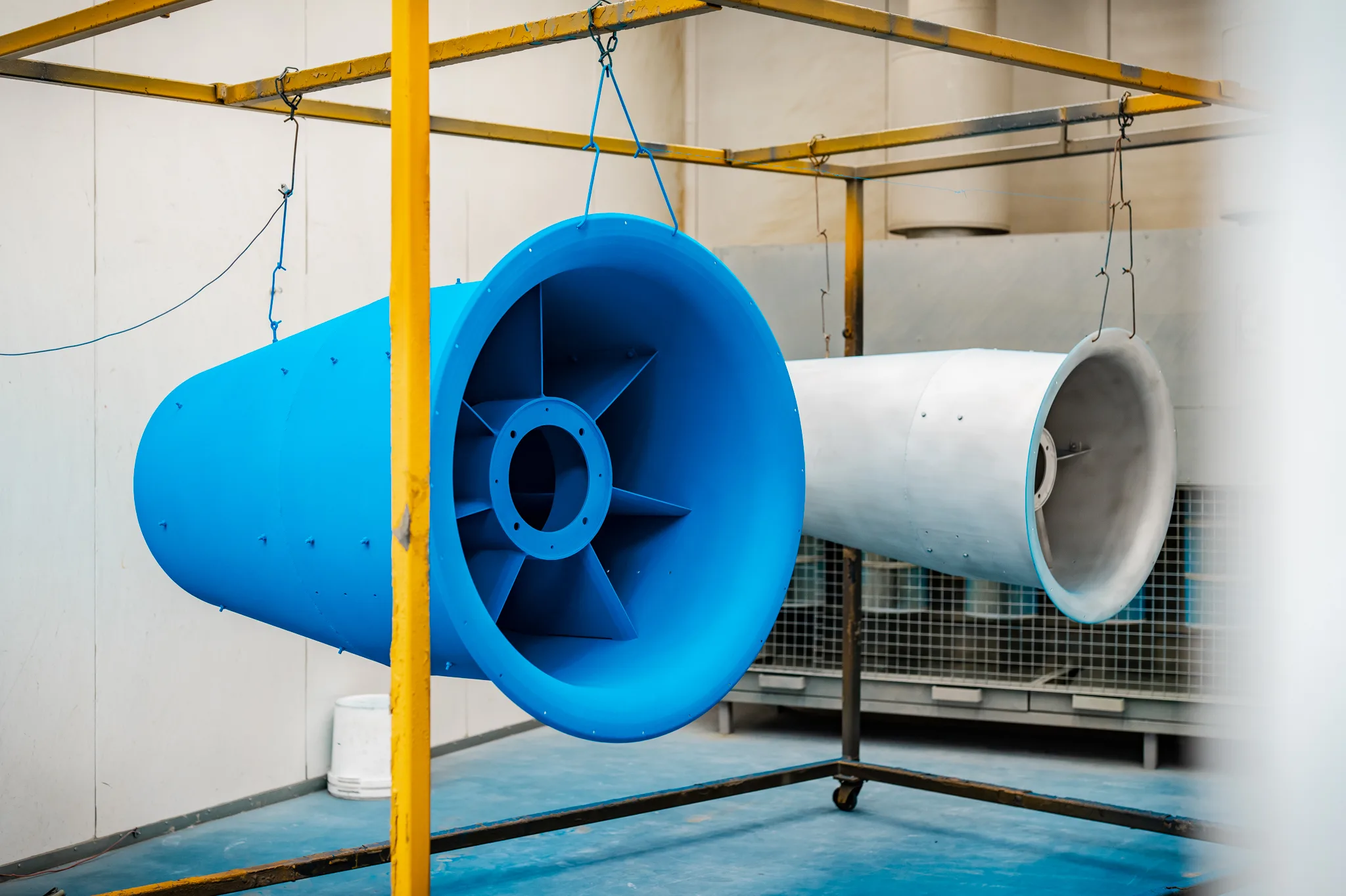 Afgewerkte blauw gecoate industriële koker met ventilatorbladen hangend in de hal van BMS Coating
