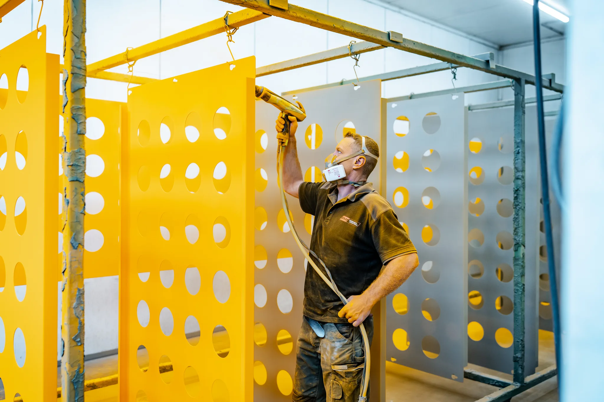 Overzicht van de productieloods en spuitcabine van BMS Coating met gele en grijze onderdelen