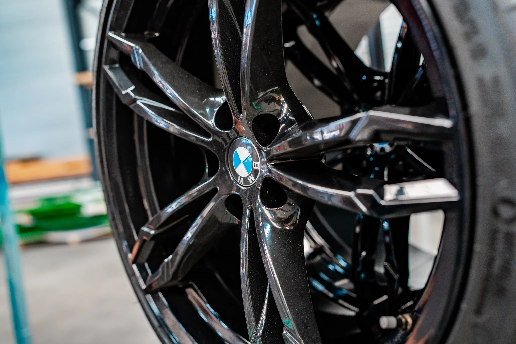 Medewerker inspecteert een zwart glans poedergecoate BMW velg bij BMS Coating