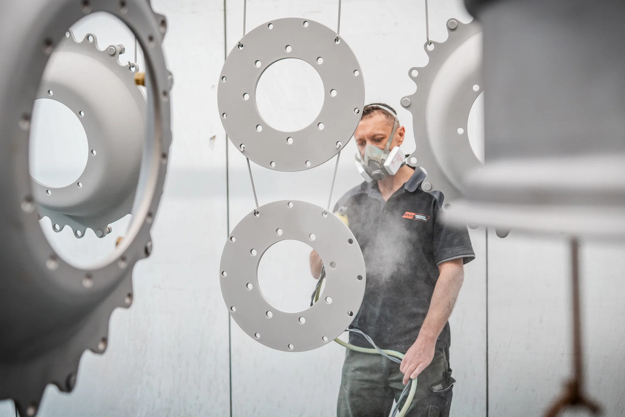 BMS Coating medewerker met spuitpistool poedercoat industriële onderdelen in spuitcabine