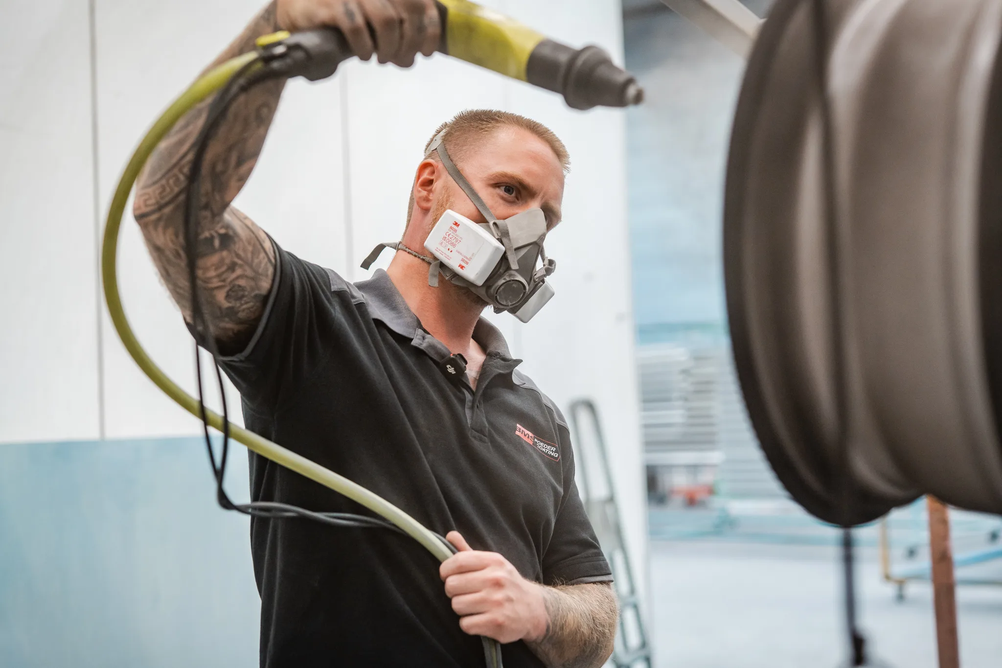 Portret van medewerker BMS Coating met spuitpistool en velg op de achtergrond