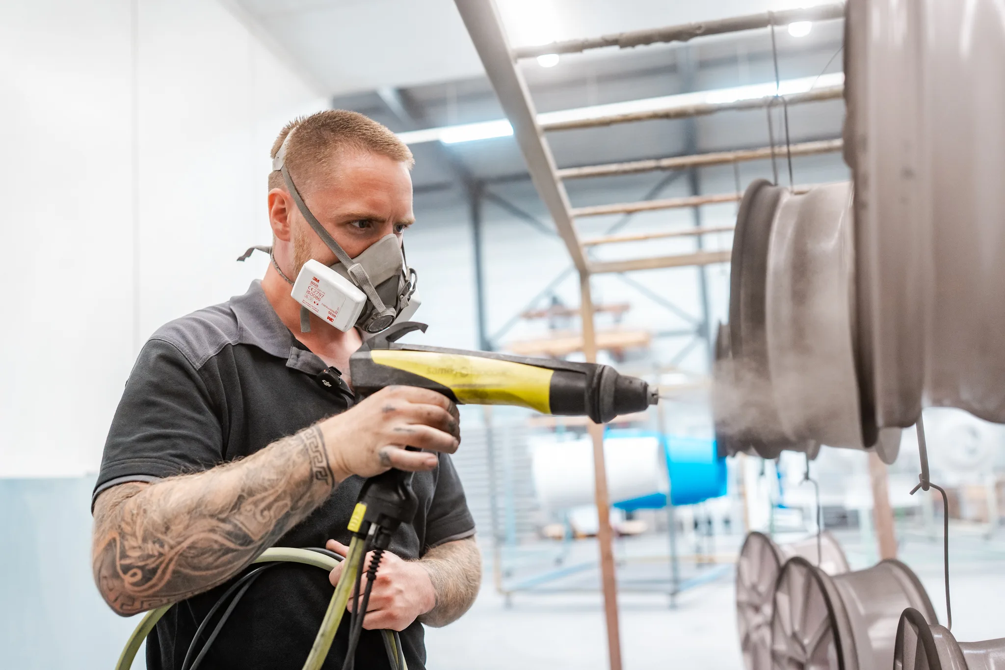 Close-up van medewerker die een velg bestuurt met spuitpistool bij BMS Coating