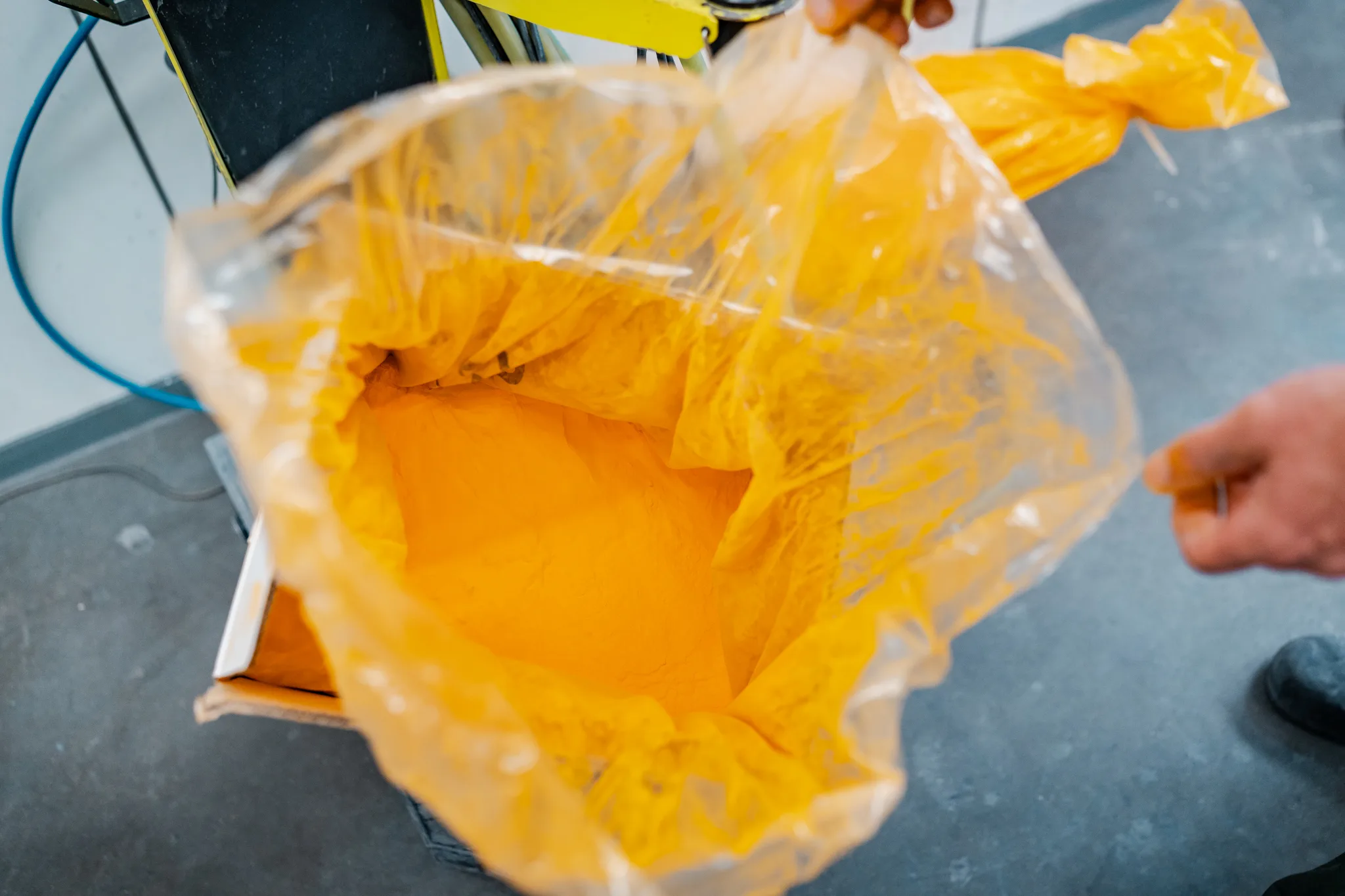 Zak met geel poedercoatpoeder wordt gevuld in de machine bij BMS Coating