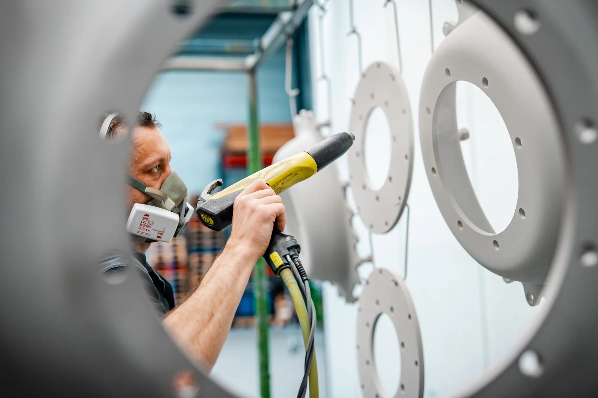 Uniek perspectief: spuitpistool door het gat van een velg tijdens poedercoaten bij BMS Coating